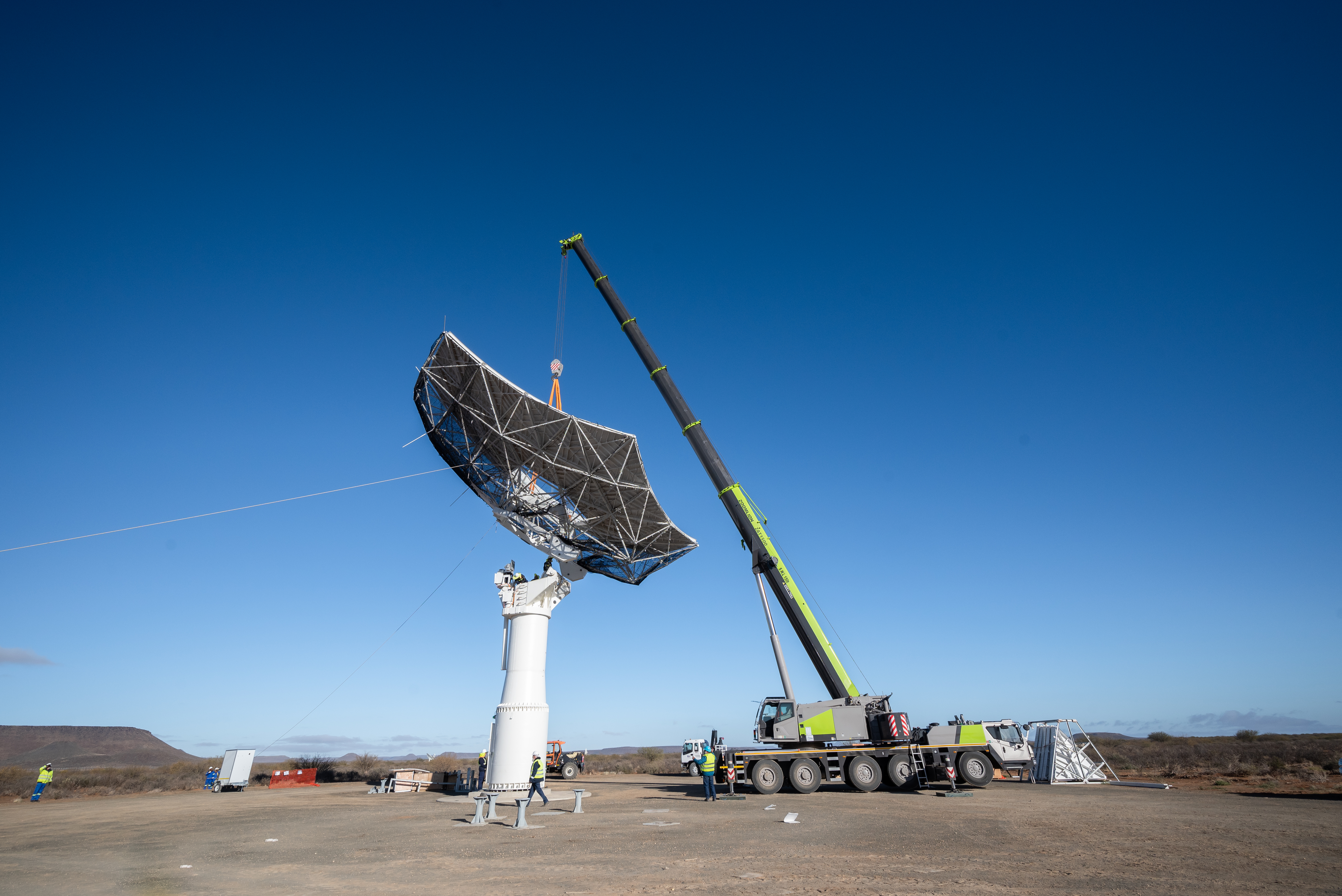 A crane places the main reflector onto the pedestal
