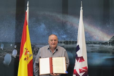 Prof. Philip Diamond holds the SKAO Convention in front of the Spanish and SKAO flags