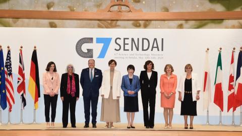 Science and technology ministers standing on stage at the G7 Science and Technology Ministers' meeting in Sendai. To the left and right are flags of the EU, US, UK, Germany, Japan, Italy, Canada and France.