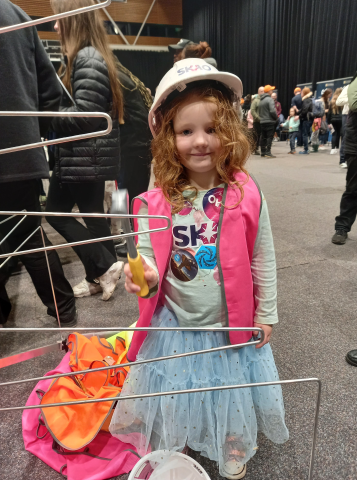 A young girl in a hard hat and a plastic hammer with an SKA-Low antenna model at Astrofest