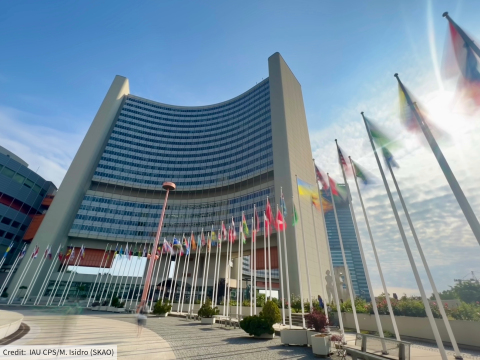 The UN building in Vienna seen from the outside, as flags fly in the foreground.