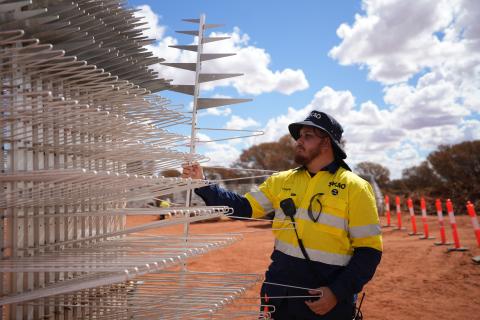 Lockie Ronan, Wajarri SKA-Low field technician, with a row of SKA-Low antennas