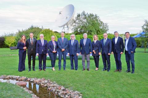 Group of people in suits in front of a big telescope dish.