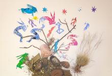 Composition of different elements: figures of animals and people sitting on a tree made from natural elements such as twigs, rocks and grass, with some stars above them. 