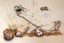 Composition of different elements: figures of animals and people sitting on a tree made from natural elements such as twigs, rocks and grass, with some stars above them. 