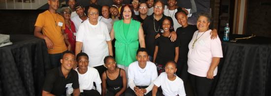 A group photos of the Carnarvon youth artists with Elders from the community. Behind them is an SKAO banner.