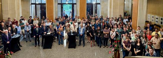 Group photo hundreds of attendees at the SKAO science meeting, in a grand entrance foyer. Some are on the ground floor, while others are standing on a mezzanine level.