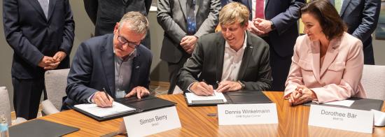 SKAO Deputy DG Simon Berry and OHB Managing Director Dennis Winckelmann sign a contract as six others look on with encouraging smiles.