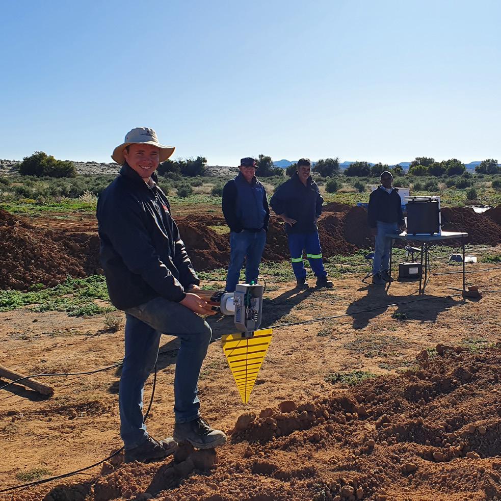 A team using an antenna to record emissions from buried cables.