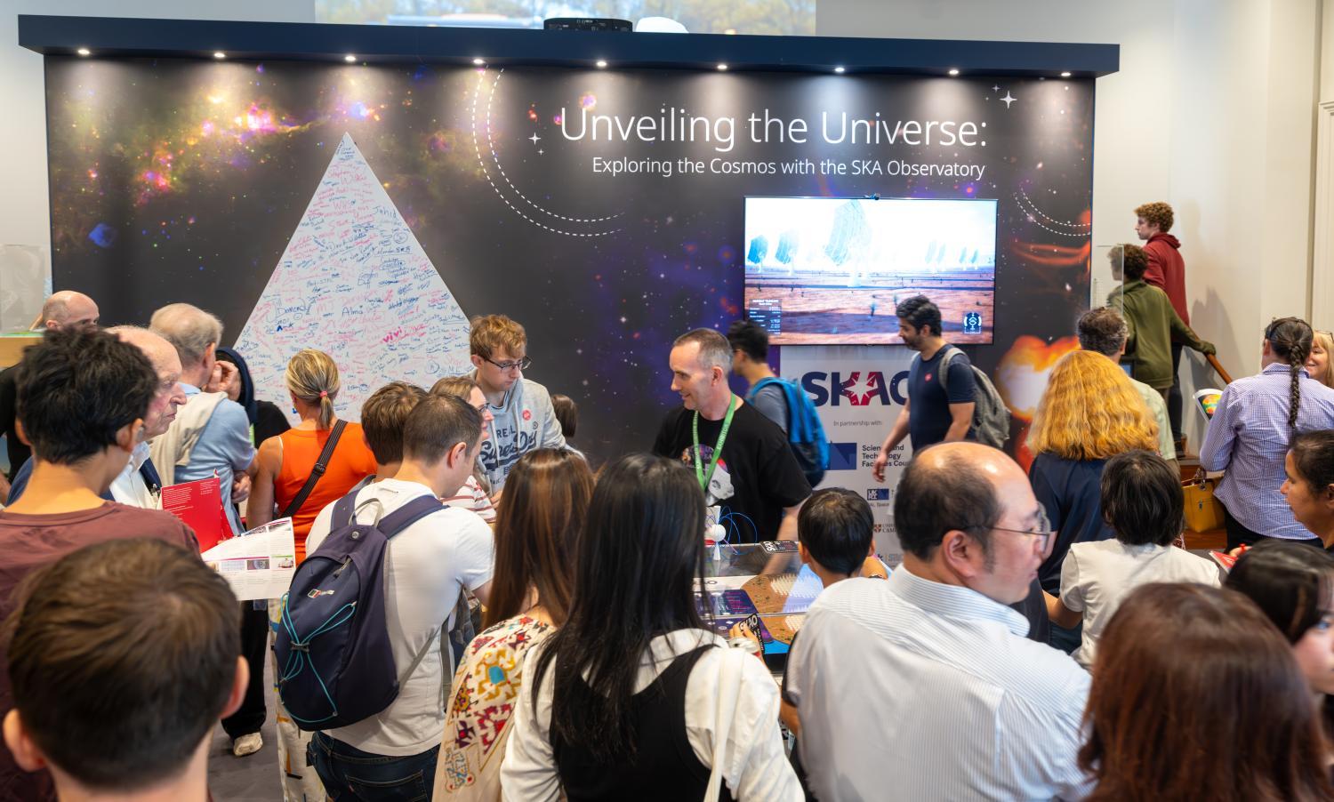 A photo of the SKAO stand at the Royal Society Summer Science Exhibition. It shows lots of people at the exhibit stand.