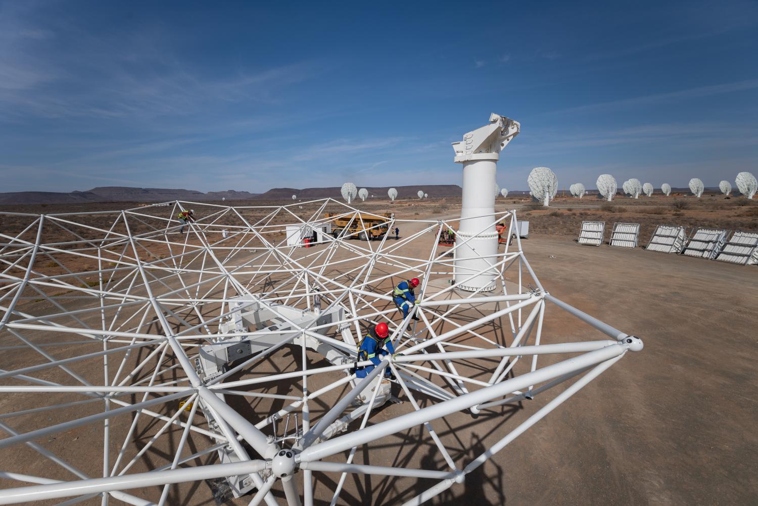An SKA-Mid dish under construction, with a person working on the structure.