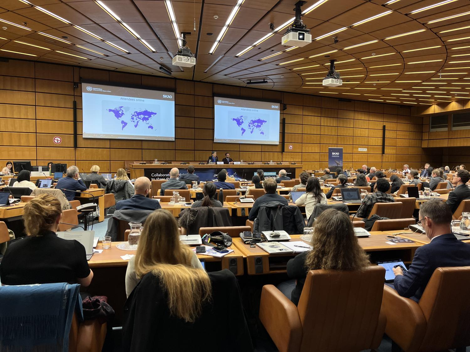 Picture of UNOOSA/SKAO meeting with two speakers sitting on stage and the audience sitting in a half-circular room.
